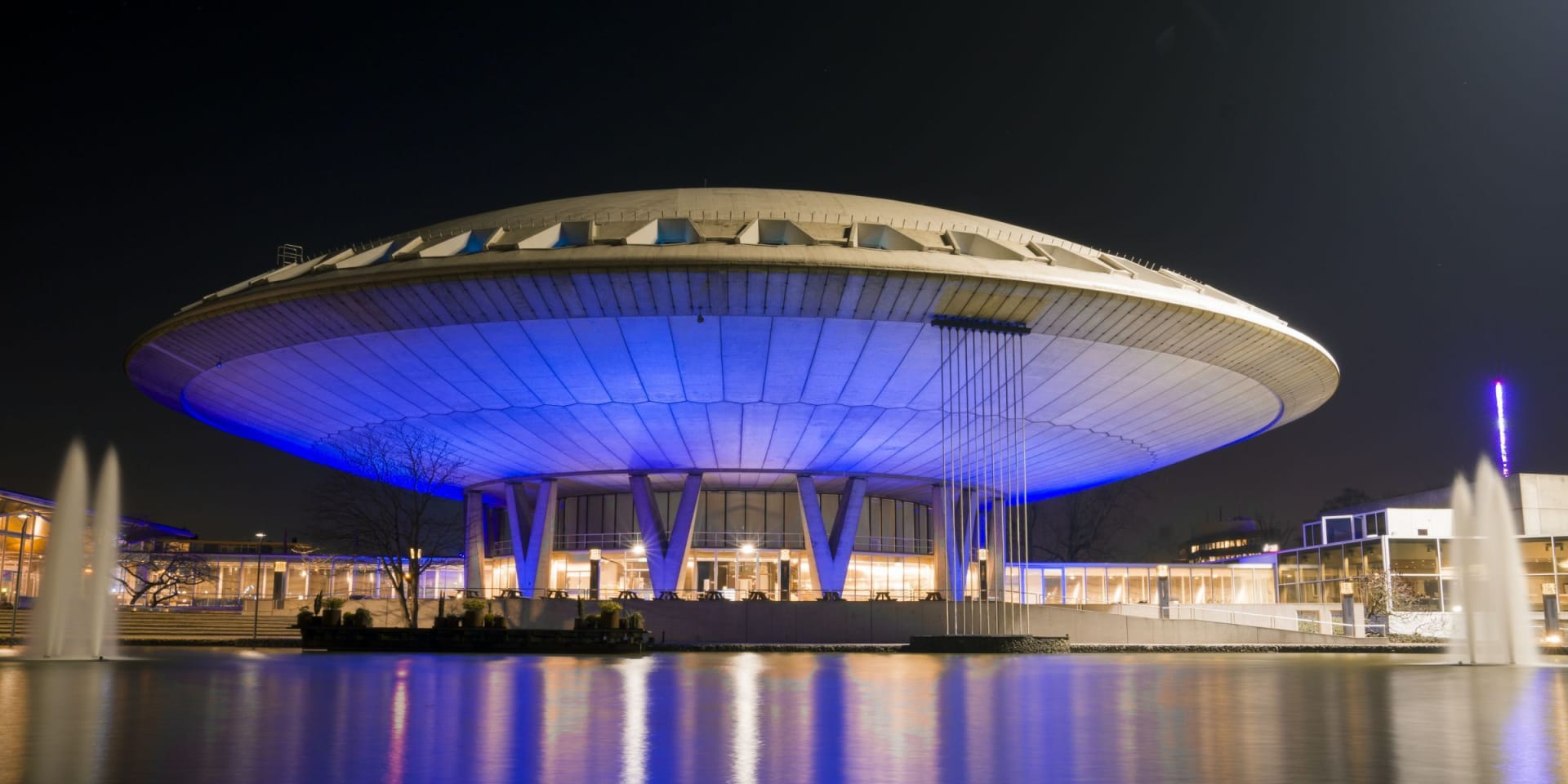 Edifício futurista iluminado à noite com luzes azuis.